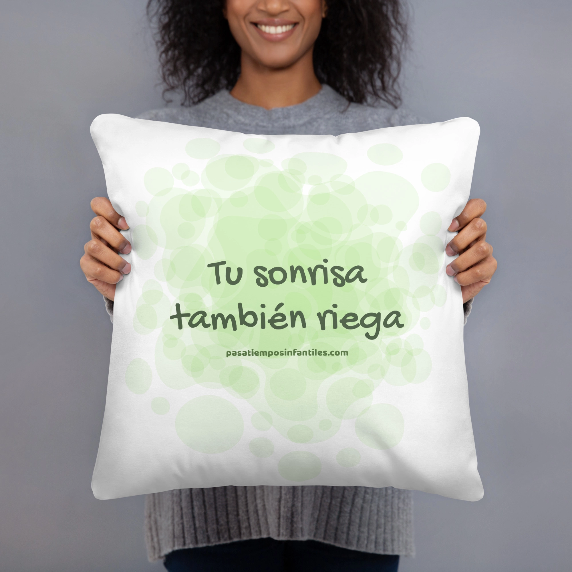 Mujer sujetando cojín con mensaje "Tu sonrisa también riega"