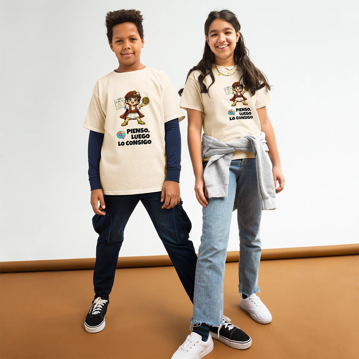 Niño y niña posando con las camisetas oficiales de Leo Polimatix en color natural, mostrando el lema de inteligencia visual-espacial