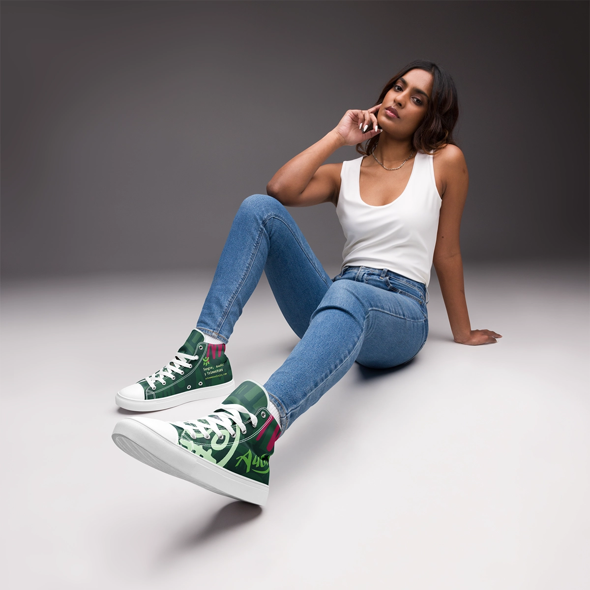 Fotografía de estudio de una modelo sentada vistiendo las zapatillas de lona altas Caza-Morosos de Autónomos Salvajes con vaqueros.